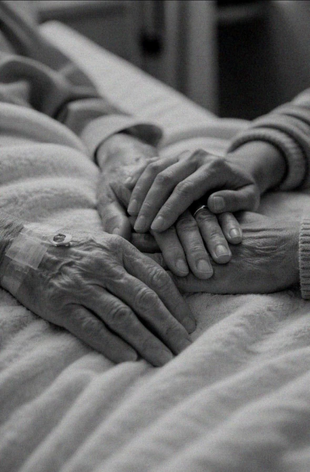A family member's hand resting gently on their elderly parent's hand